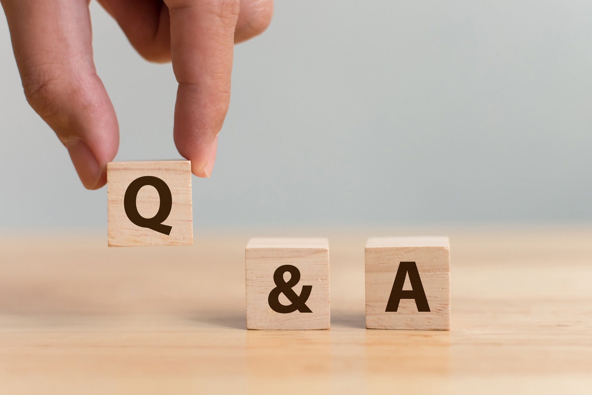 Questions and answers concept. Hand putting wood block cube with alphabet Q&A on wooden table